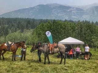 Group of riders preparing to ride in mountains with a small vendor tent in background