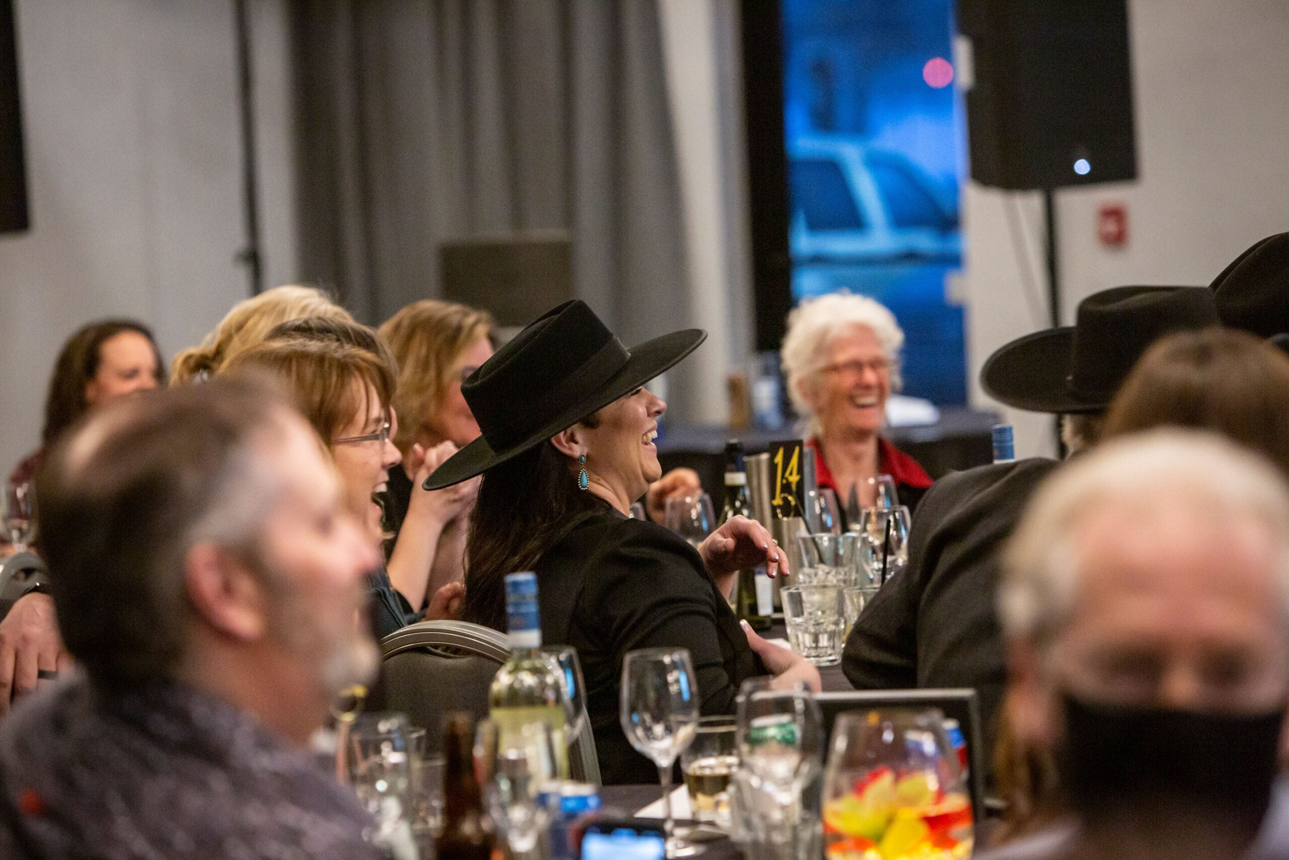 Room full of people enjoying the evening with focus on lady in hat