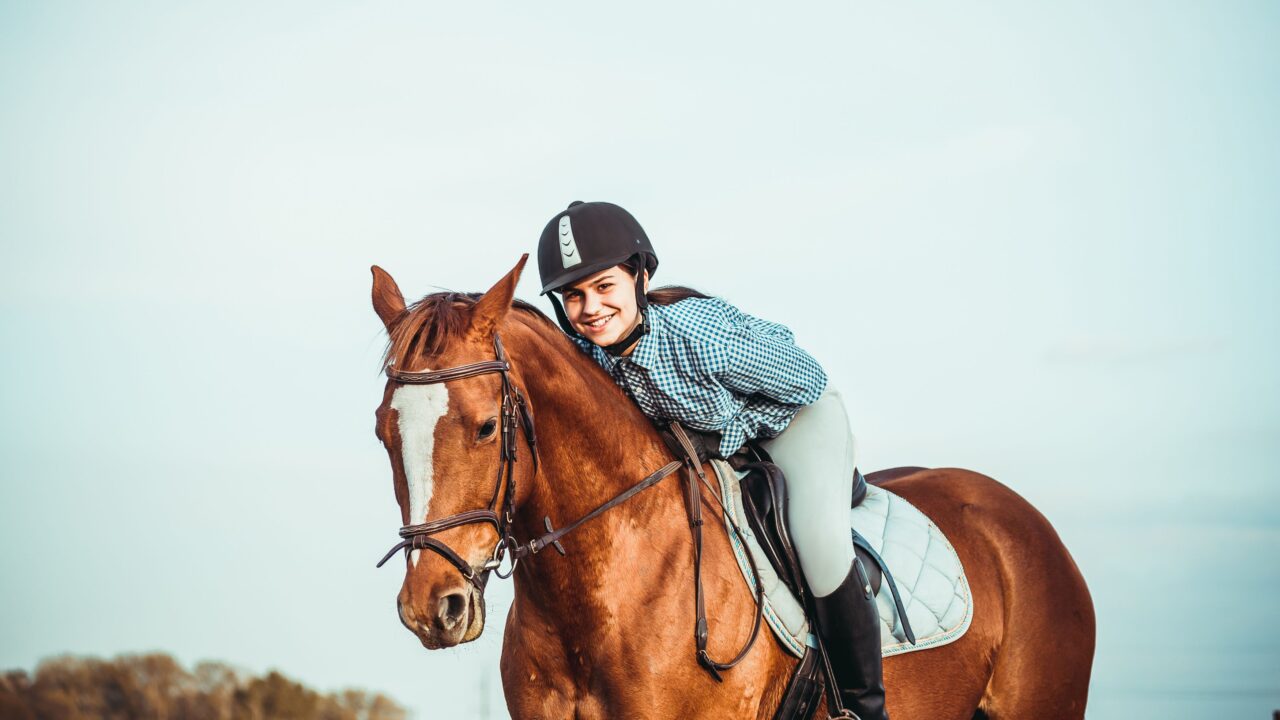 Young woman on a chestnut horse wearing a helmet